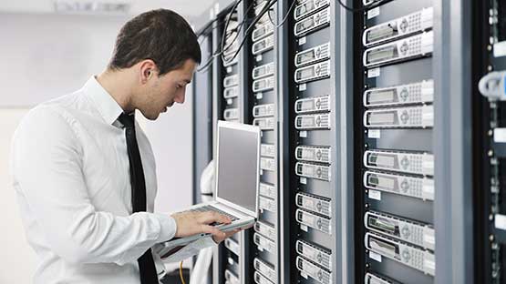 Computer technician working on a laptop inside a data center