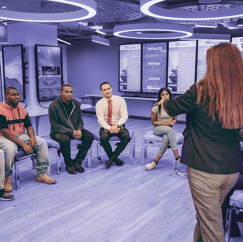 Group of young professionals sitting in a room while a presenter is speaking