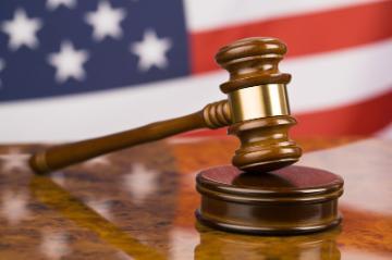 A judge's gavel with the American flag in the background